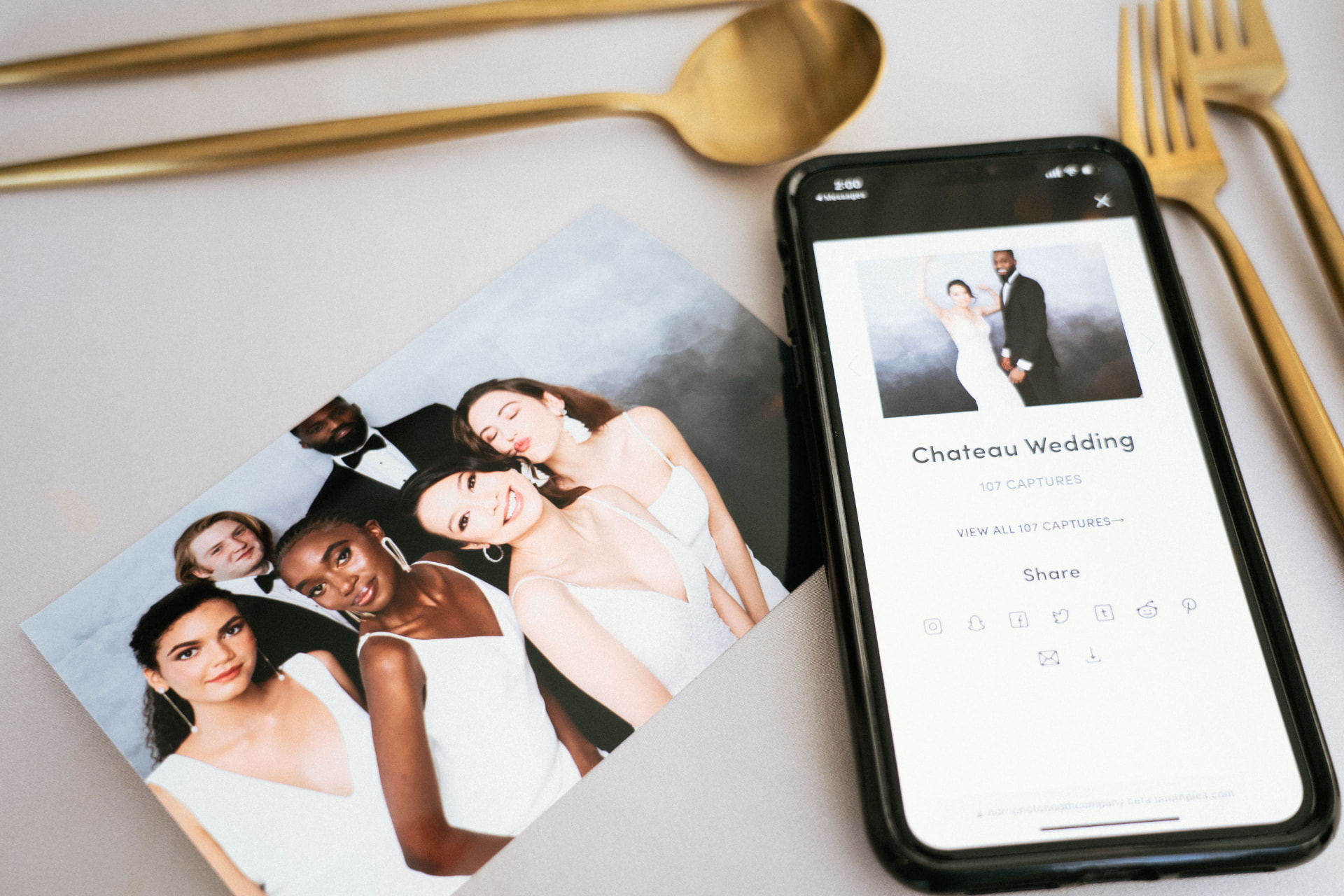 A Palm Tree Photo Booth print beside a phone displaying the live online wedding gallery